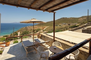 A terrace with lounge chairs, a table, and a view of the sea.