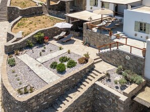 A rooftop patio with stone walls, seating areas, and potted plants.