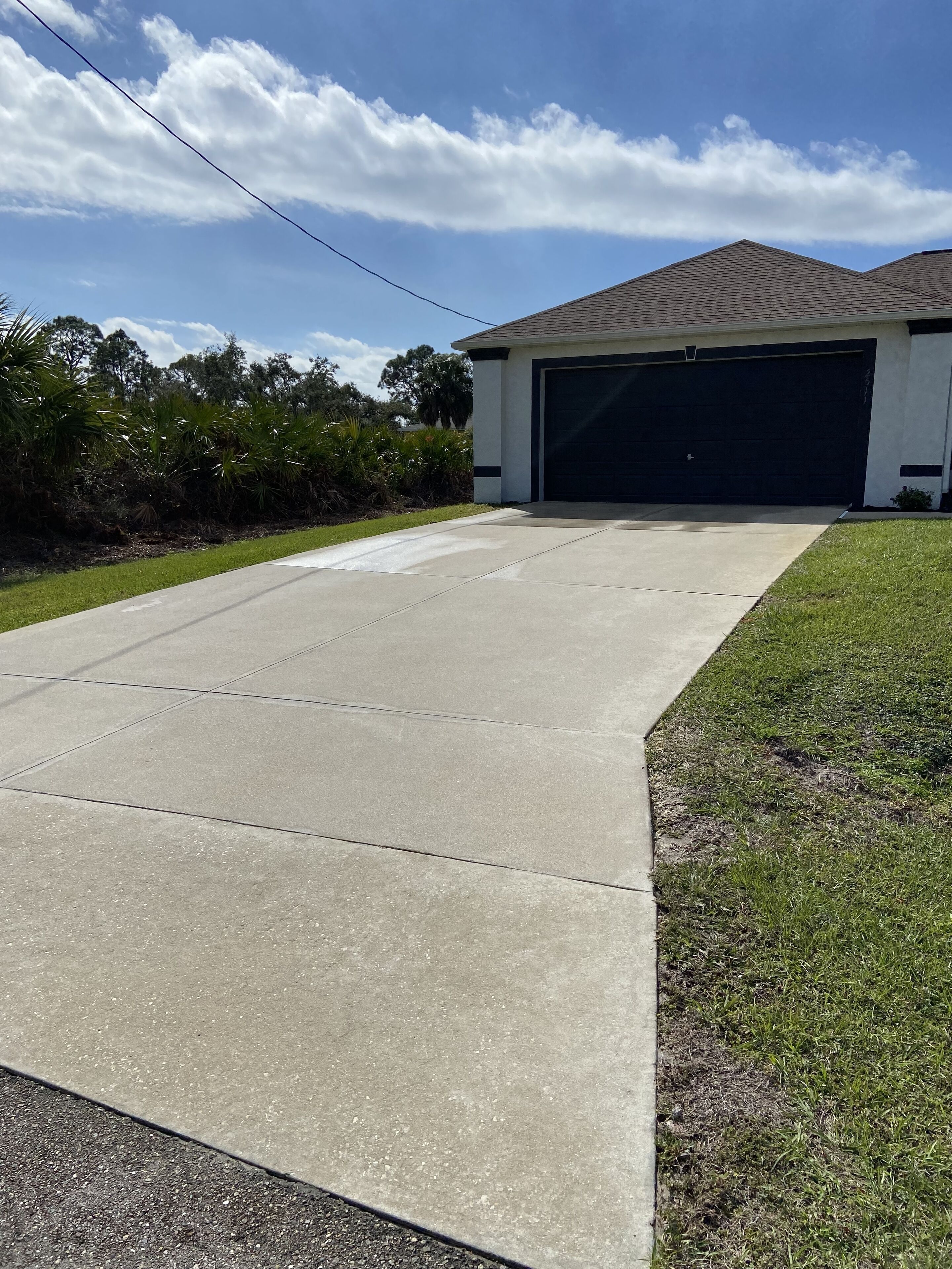 A residential driveway leading to a garage with a dark-colored garage door.