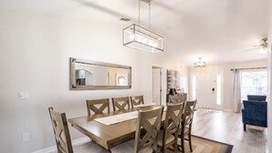 Un coin repas avec une table et des chaises en bois, un luminaire suspendu et un miroir au mur.