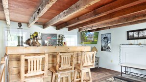 Una cocina rústica con taburetes de madera, encimera de madera y techo de madera con vigas a la vista.