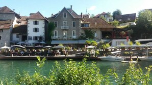A riverside restaurant with outdoor seating, a dock, and a boat.