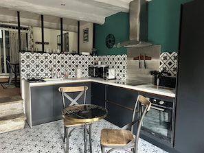 A kitchen with a central island, two chairs, a stove, and a sink.
