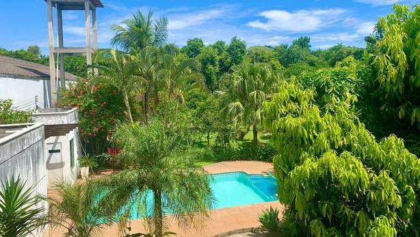 A swimming pool surrounded by lush greenery and a water tower. - chacaradaspalmeiras512 -Inoan-Marica-RJ-lots of greenery, swimming pool, sauna, (marica)