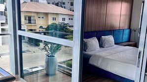 Un dormitorio moderno con un ventanal grande, una cama, una mesita de noche y una planta en maceta.