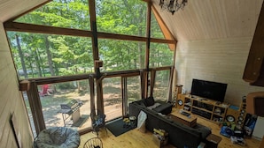 Un amplio espacio de sala con un ventanal grande, un sofá, un televisor y piso de madera.
