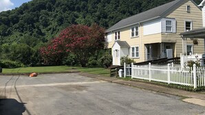 Une rue résidentielle avec une maison, une clôture blanche en bois et une montagne en arrière-plan.