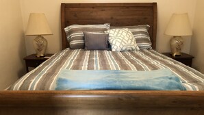 Un lit avec une literie à rayures, un plaid bleu et deux lampes de chevet.
