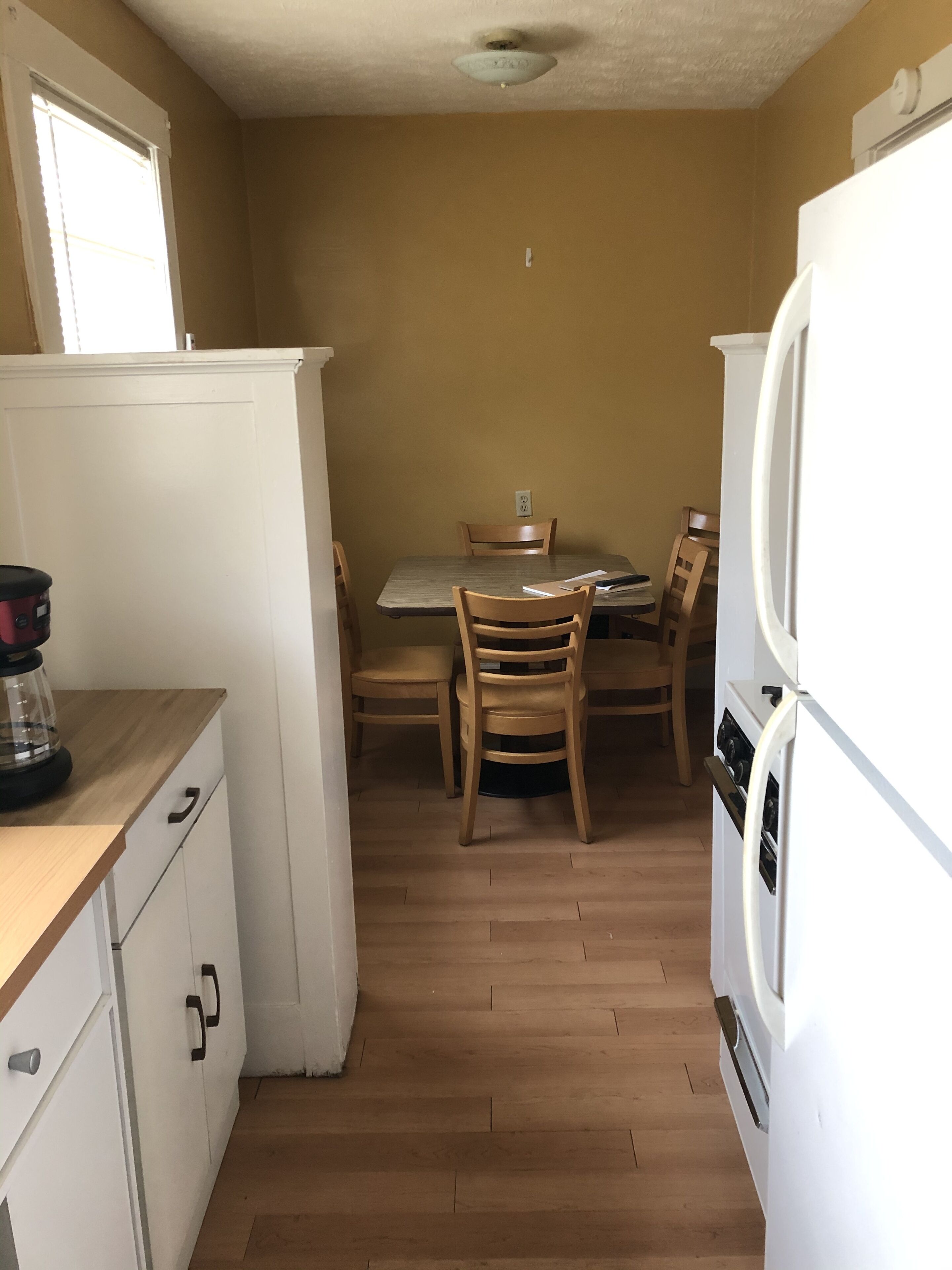 Una cocina compacta con armarios de madera, una mesa de comedor con sillas y un refrigerador.