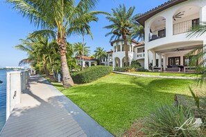 A waterfront property with a wooden deck, palm trees, and a well-maintained lawn. - 11br Villa Calabassa on the Water (Miami)