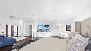 Un espacio habitable amplio con una cama grande, un sofá azul y vistas al océano a través de una ventana.