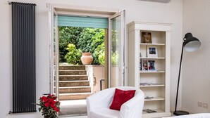 Ein Wohnzimmer mit weißen Möbeln, einem weißen Couchtisch, einer roten Vase und einem Bücherregal.