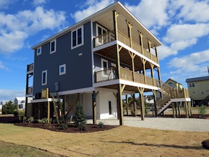 A two-story house with a balcony on the upper floor, a covered porch on the ground floor, and a wooden deck.