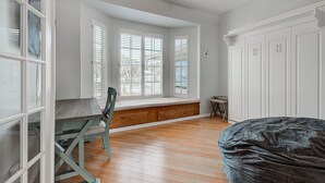 Une pièce dotée d’un grand siège de fenêtre, d’un plancher en bois et de meubles blancs.
