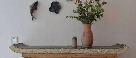 A wooden console table with a vase of flowers, a small decorative item, and wall decorations including fish and a flower.