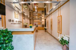 A hotel lobby with a reception desk, a wooden reception area, and a corridor leading to the rooms. - Kunmin Xiangmei Bangpo Hotel (Kunming)