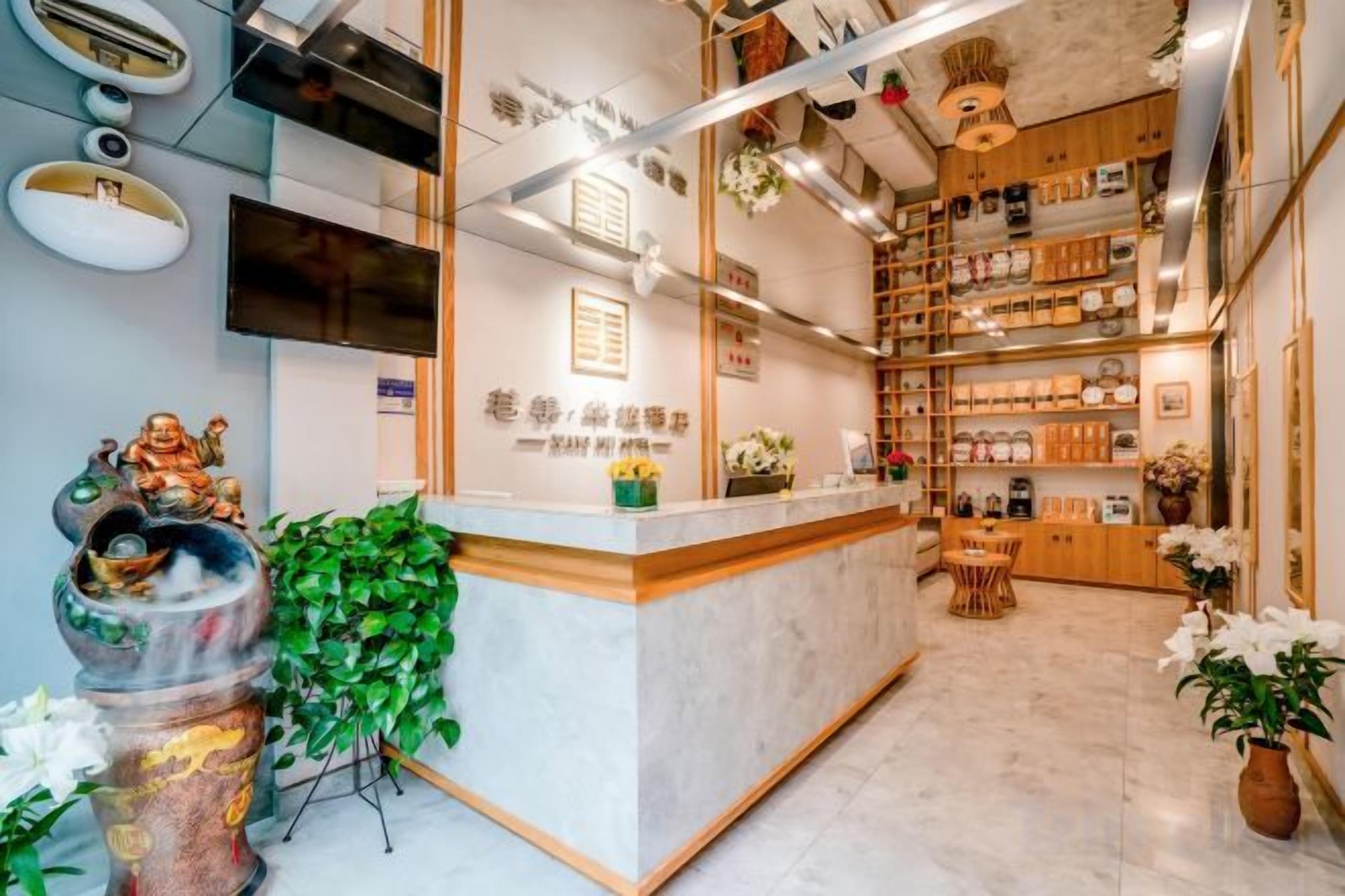 A reception area with a marble counter, wooden shelves, and a television.