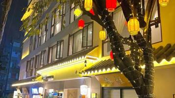 A building with multiple floors, illuminated by warm interior lighting.