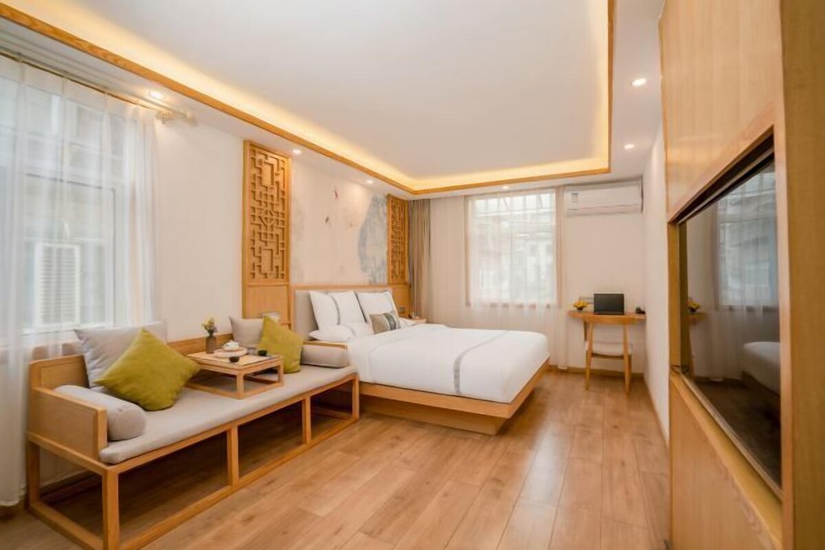 A modern bedroom with a bed, a sofa, a small table, and a desk.