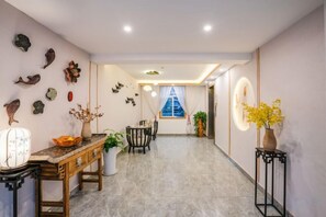 Un couloir comprenant un coin repas, une table avec un vase et un mur orné d’objets décoratifs.