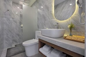 Un baño moderno con un lavabo grande blanco, un inodoro y una zona de ducha.