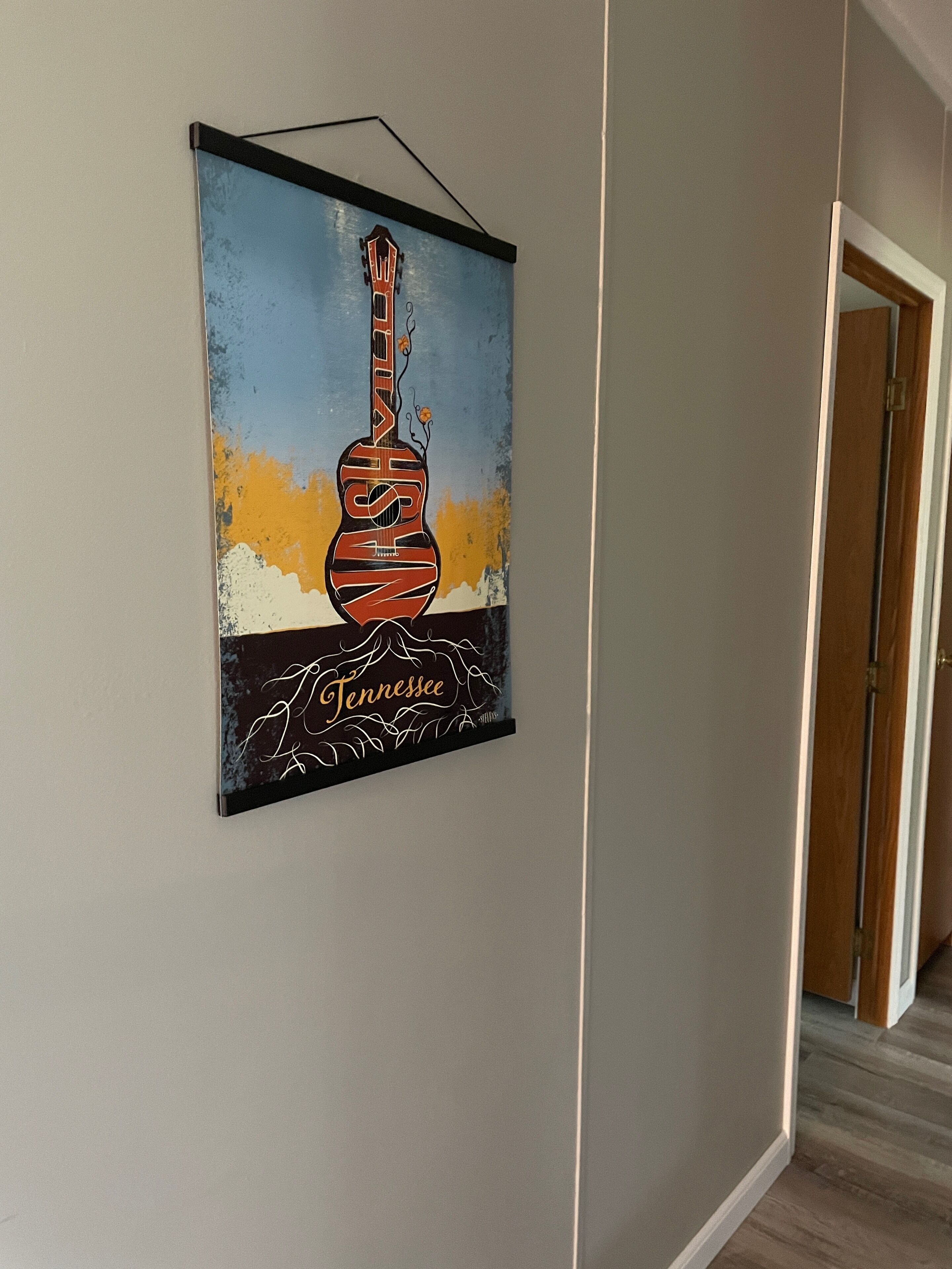Uma moldura na parede com uma obra de arte que mostra um violão e a palavra "Tennessee".