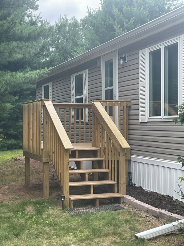 A residential house with a wooden deck and a set of stairs leading to a covered porch. - Secluded remodeled Cabin•Walk to Castle Rock Lake & restaurants•Firepit•Deck (New Lisbon)