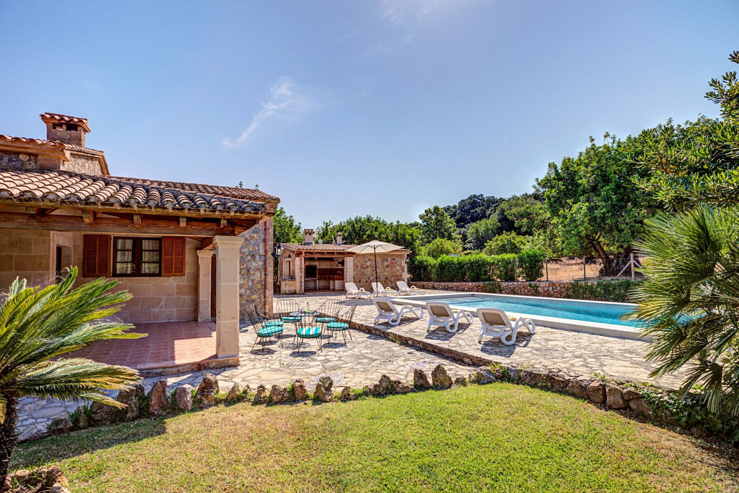A villa with a swimming pool, outdoor seating, and a garden.