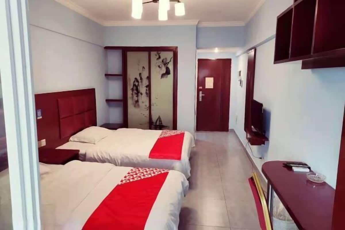 Habitació d'hotel amb dos llits, un televisor, una taula de treball i un armari.