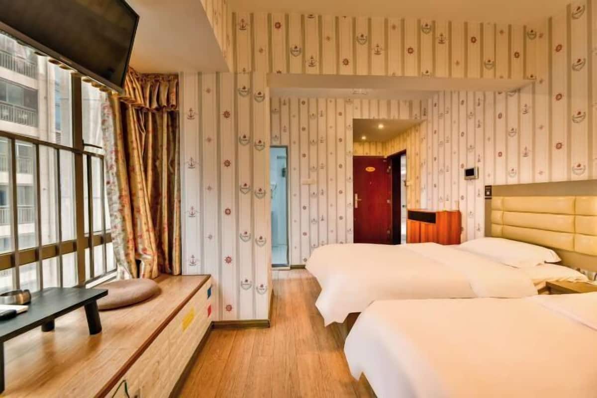 Habitació d'hotel amb dos llits, un escriptori de fusta i una televisió.