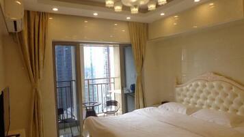 A hotel room with a large bed, a chandelier, a balcony with a chair, and a view of the city.