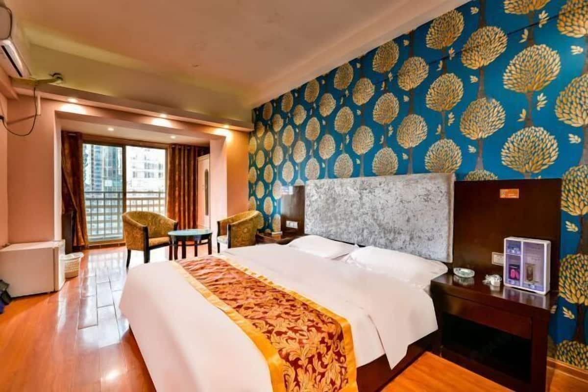 Habitació d'hotel amb un llit gran, escriptori, cadira i un mur amb un disseny decoratiu.