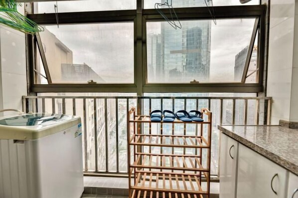 A kitchen with a window, a water dispenser, and a shoe rack. - Chenxi Hotel Apartment (Nanning)