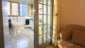 A room with a large window, a sofa, and a table with chairs. - Chenxi Hotel Apartment (Nanning)