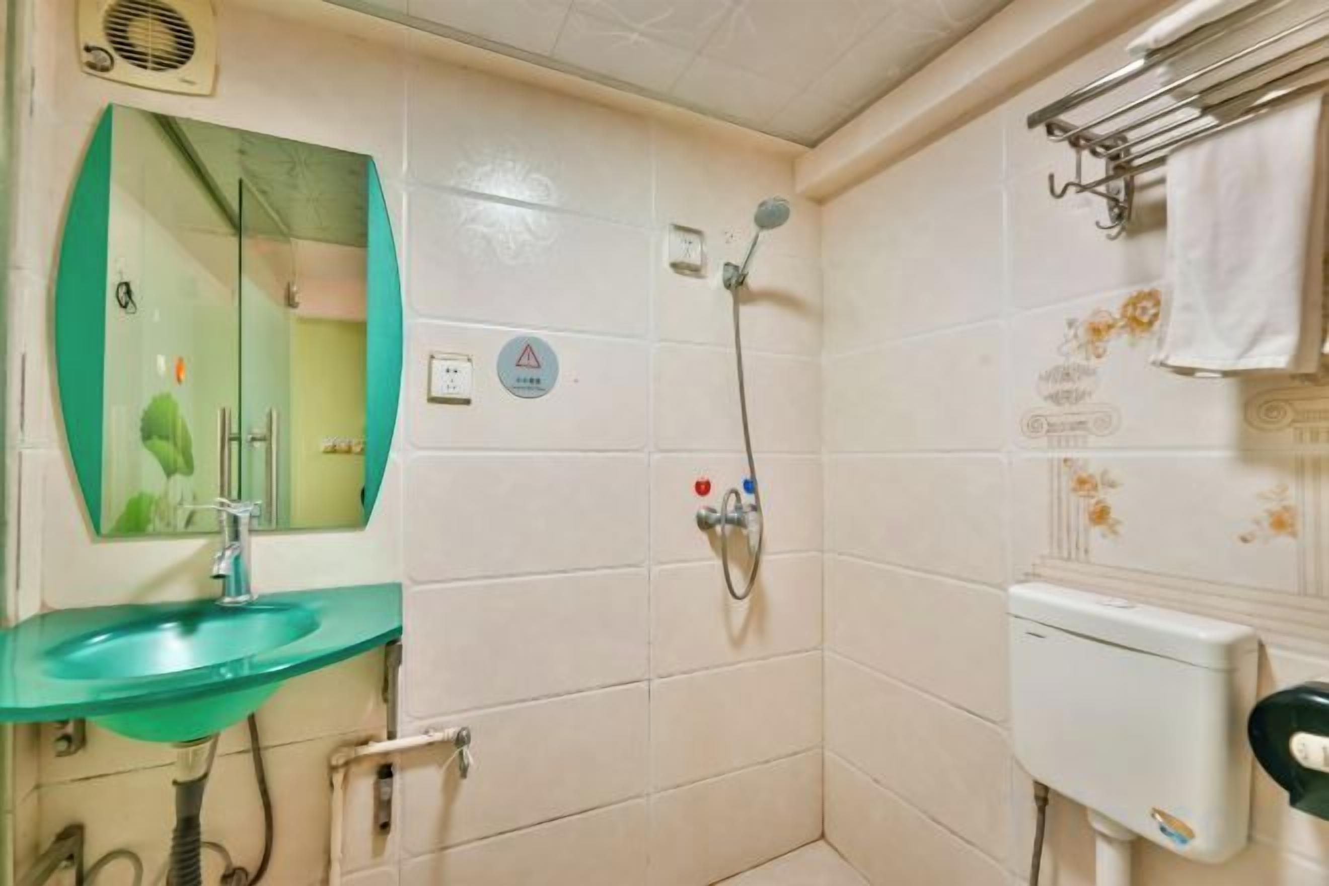 A bathroom with a sink, mirror, shower, and towel rack.