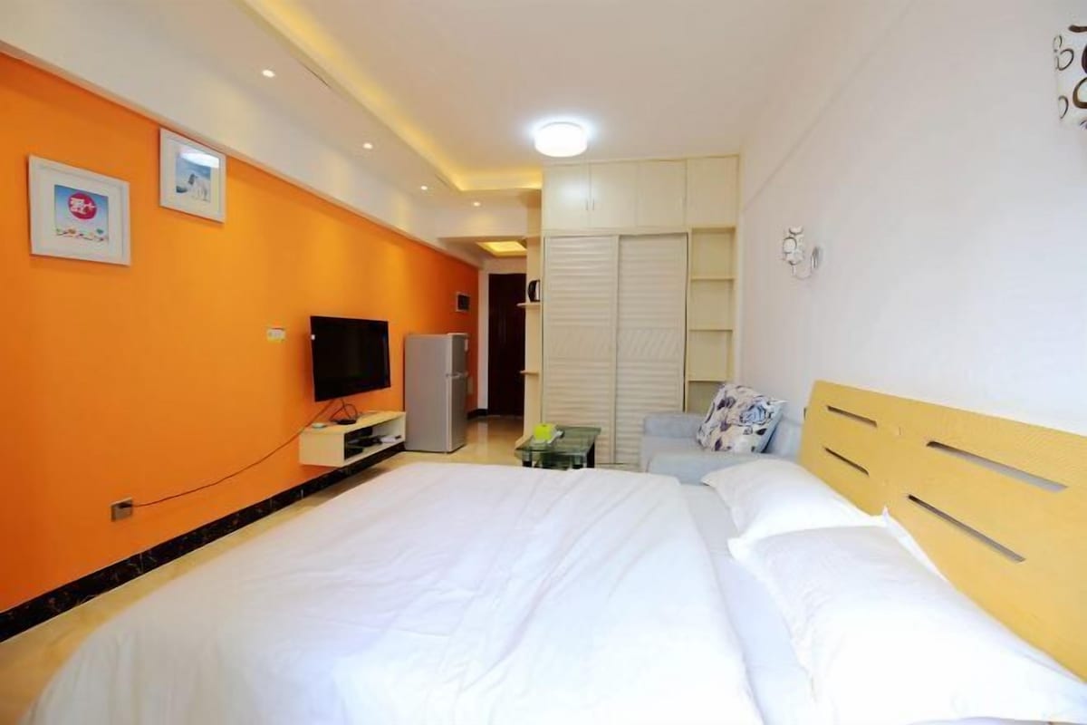 Una habitación de hotel con cama, televisión, refrigerador y armario.