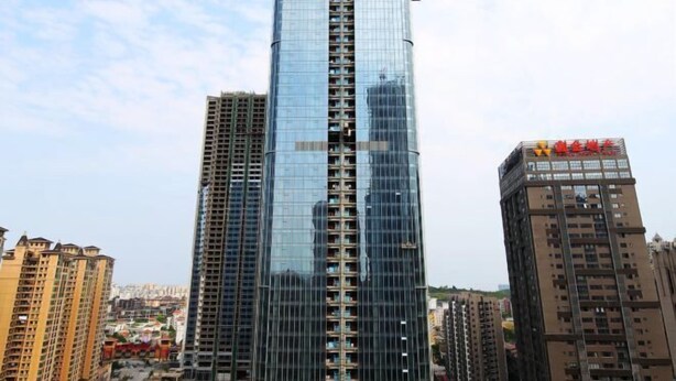 A tall, modern skyscraper with a glass facade, surrounded by other buildings. - Chenxi Hotel Apartment (Nanning)