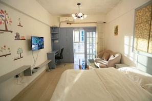 A bedroom with a bed, a desk, a TV, a chair, and a wardrobe. - Chenxi Hotel Apartment (Nanning)