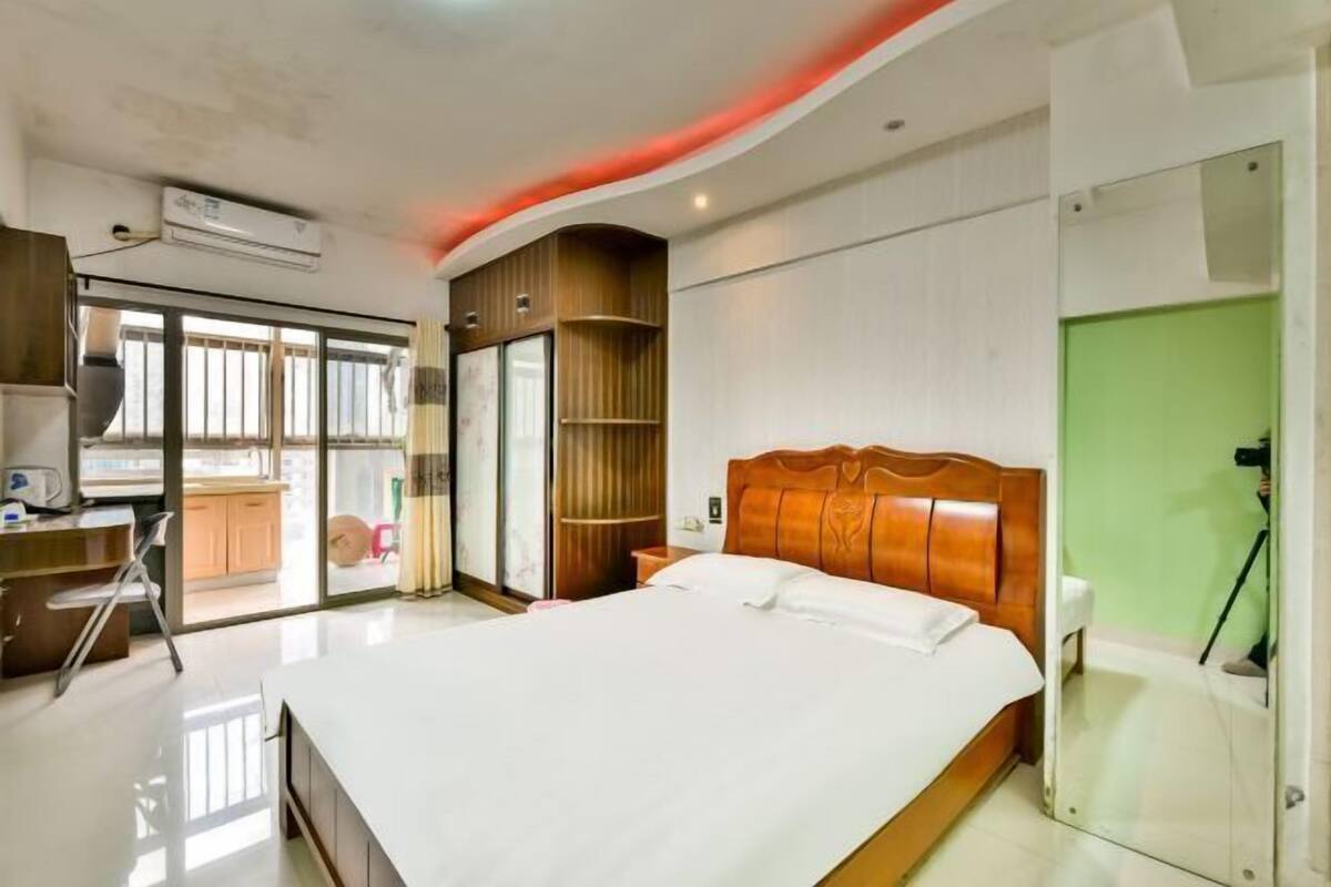 Una habitació d'hotel moderna amb un llit gran, una taula de treball i una porta corredissa de vidre que dona a un balcó.