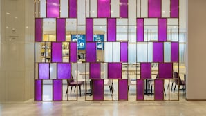A hotel lobby with a modern design, featuring a partition with purple panels and a reception desk in the background. - Lavande Hotel (Haikou)