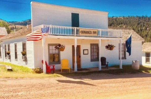 Welcome to Bonanza Inn, a charming two-story building with a balcony and seating area outside the entrance.