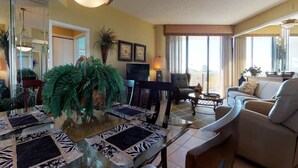 A living room with a dining table, chairs, a sofa, and a television.
