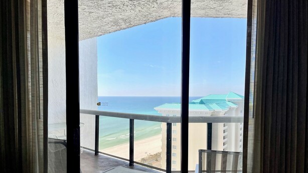 A balcony with a view of the ocean and a building with green roofs.