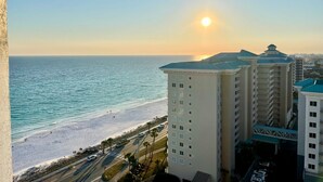 A beachfront hotel with a view of the ocean and sunset.