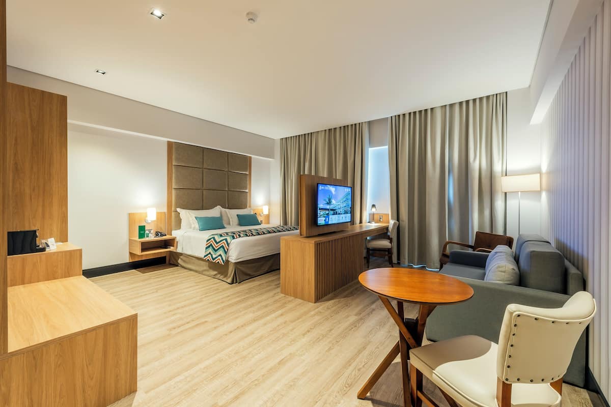 A modern hotel room with a bed, a desk, a TV, and a sofa.