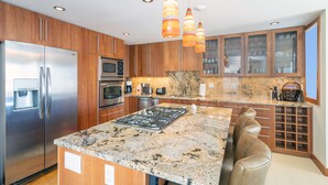 Una cocina moderna con electrodomésticos de acero inoxidable, encimeras de granito y armarios de madera.
