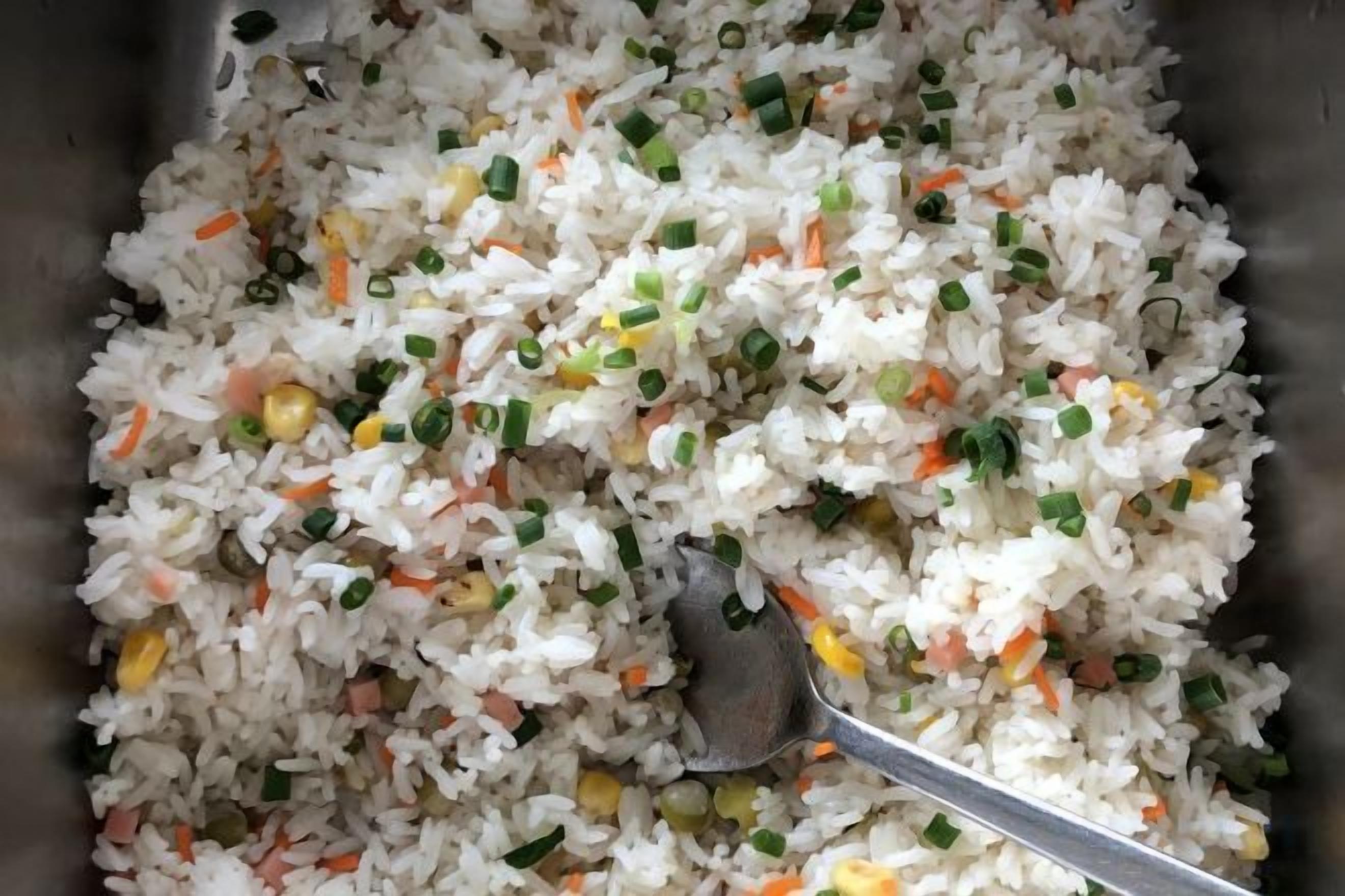 A close-up of a dish with rice, vegetables, and green onions.