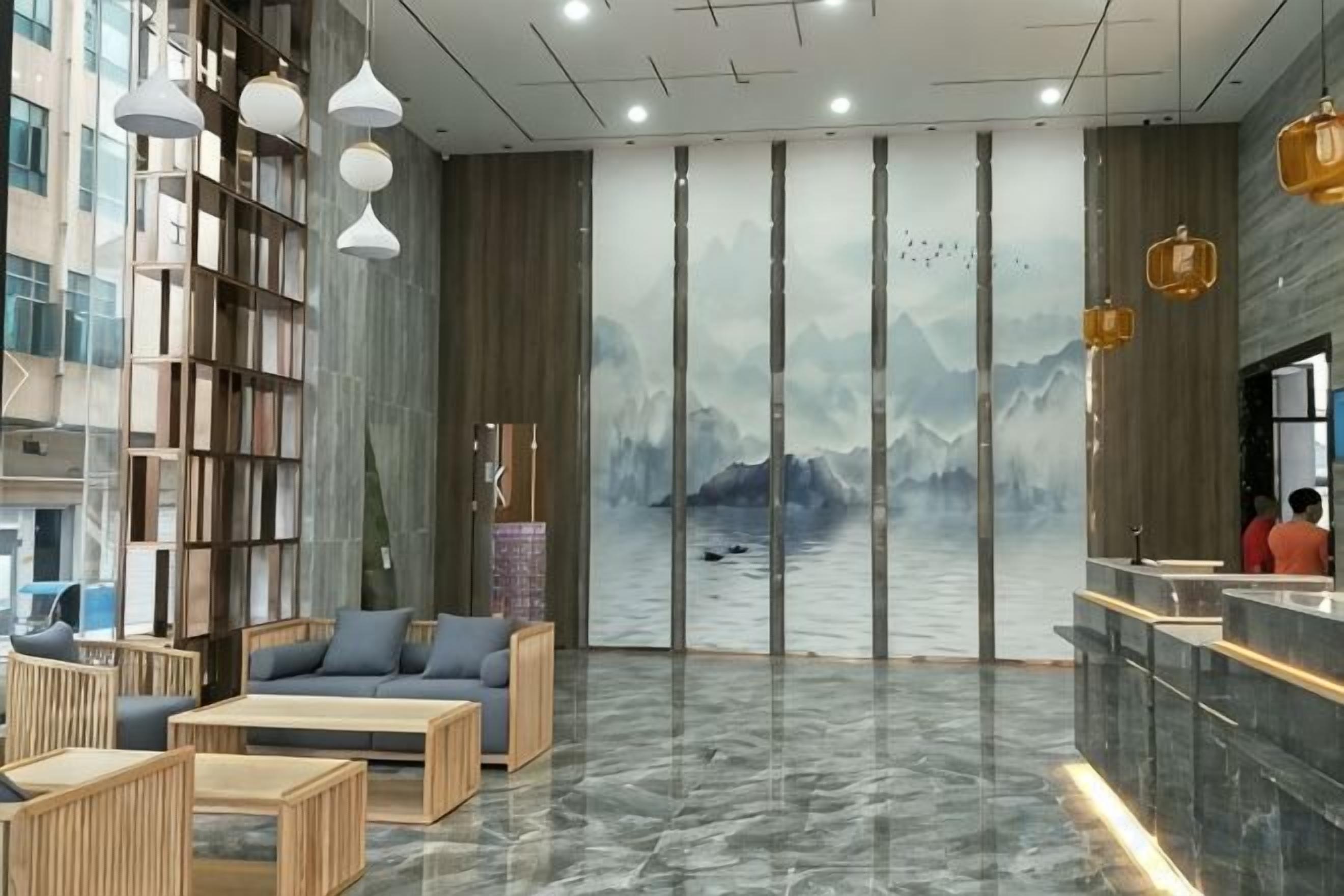 A modern lobby with a reception desk, seating area, and a large mural of mountains and water.
