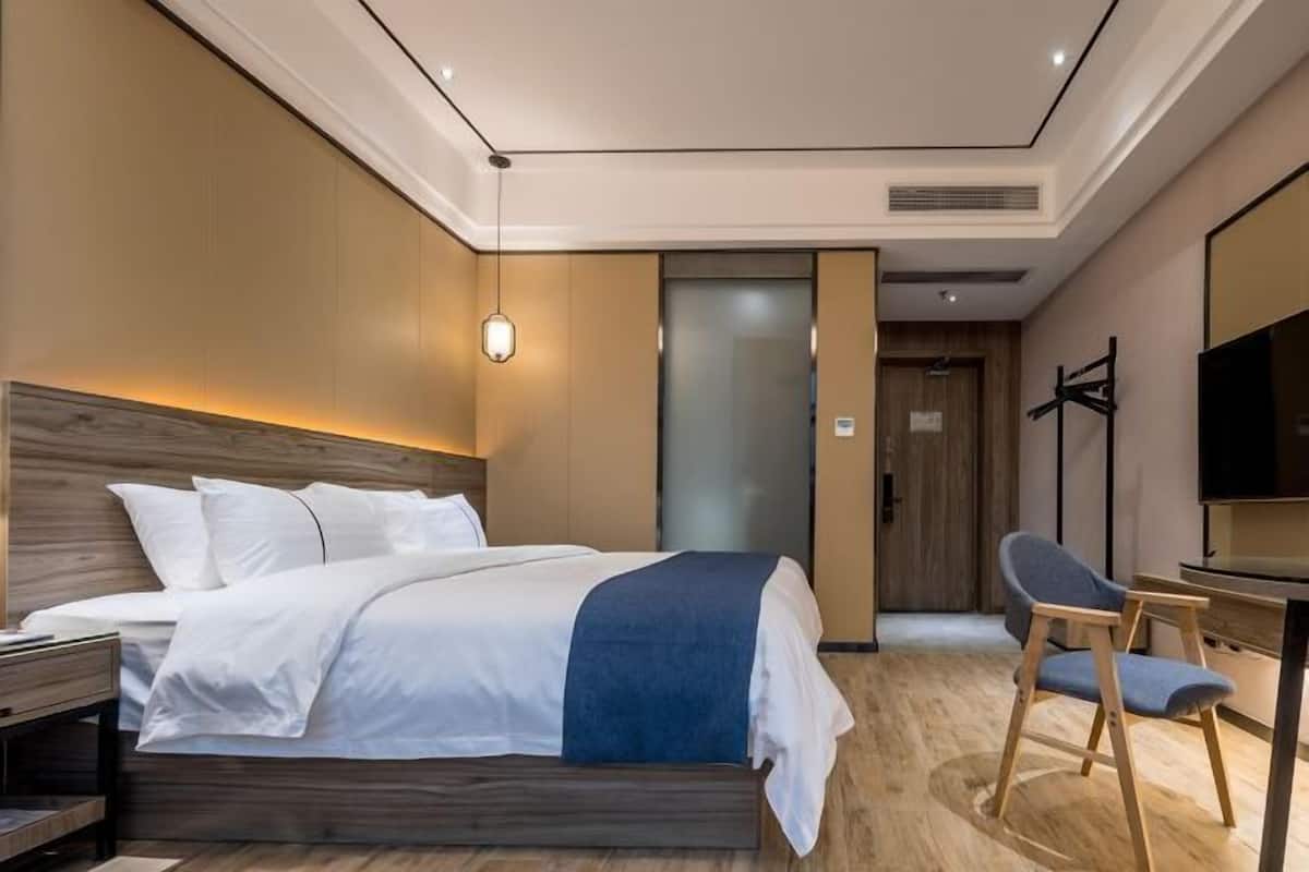 A modern hotel room with a large bed, a desk, and a television.