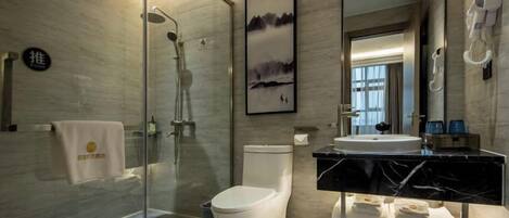A modern bathroom with a glass-enclosed shower, a toilet, and a vanity with a black marble countertop.